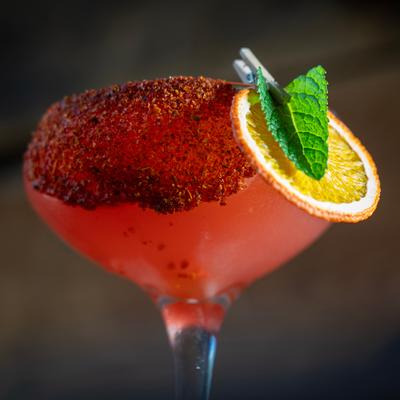 Watermelon craft cocktail with tequila, chili rim, orange slice, and mint.