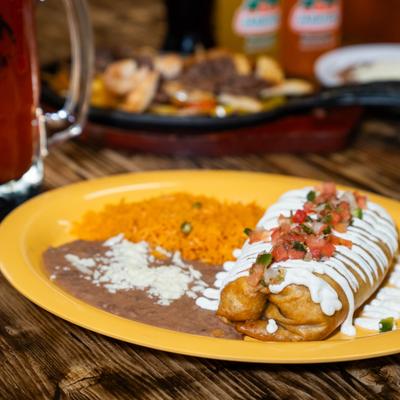 Chimichanga with sour cream and tomato salsa, served with rice and beans.