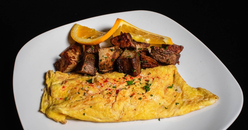 Omelet with roasted potatoes, garnished with orange wheel