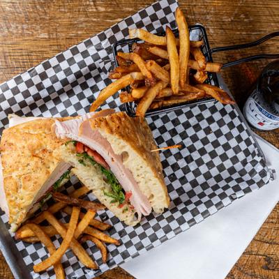 Turkey club sandwich with fries and bottled beer, top view.