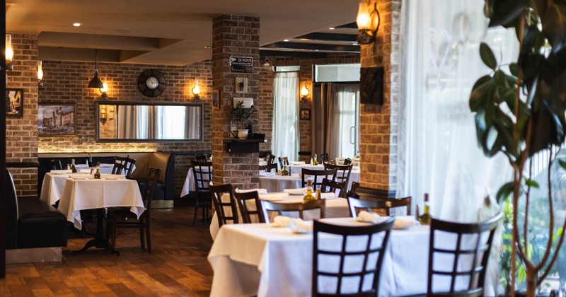 Interior seating area with brick walls and tables set with white tablecloths