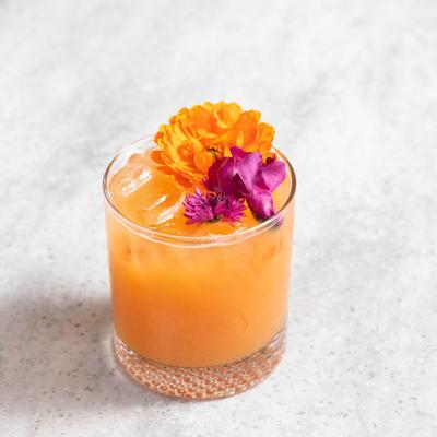 A vibrant cocktail garnished with flowers.