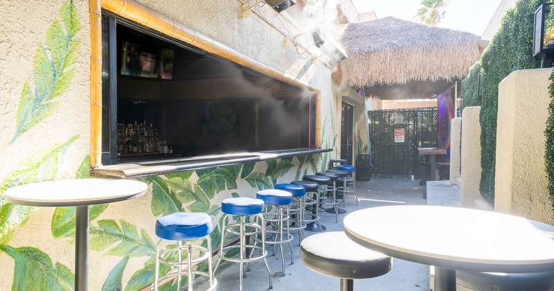Outdoor bar area with stools and a leaf-painted wall