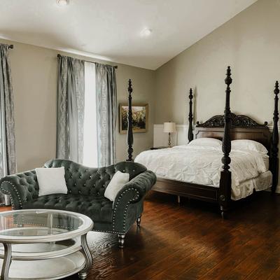 Bedroom with a pencil post bed, vintage furniture, wall art, and curtains.