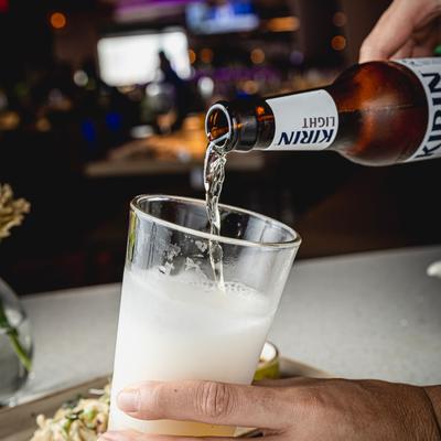 A person pouring a light beer into a glass.