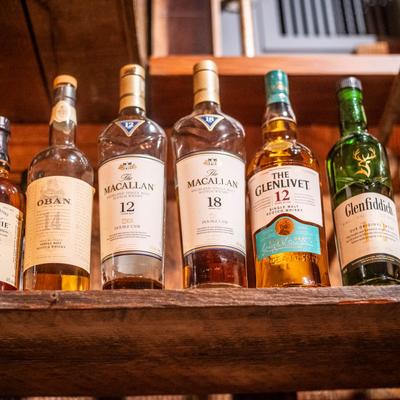 A collection of Scotch whiskey bottles displayed on a wooden shelf.