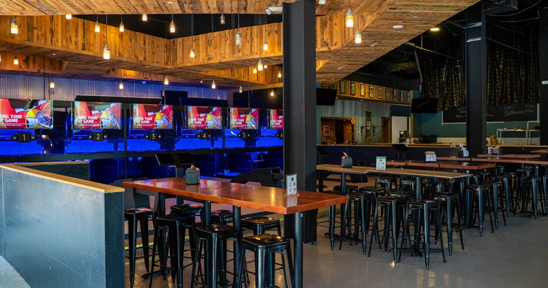 Interior, high seating area, high wooden top tables with metal stools, concrete flooring