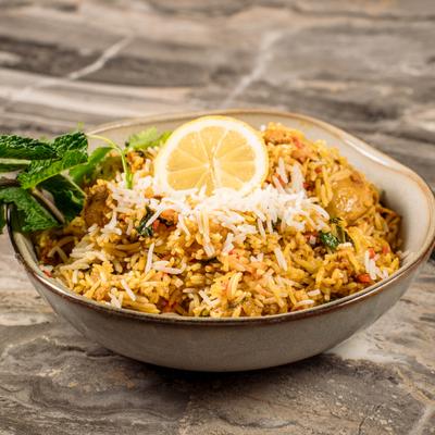 A bowl of Chicken Biryani on a marble table.
