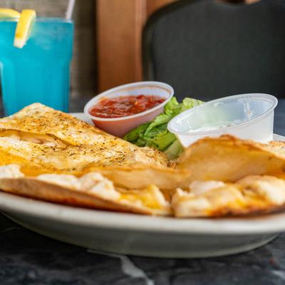 Chicken quesadilla served with red salsa and sour cream.