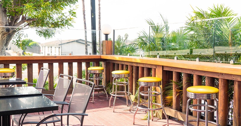 Patio, tables, chairs and yellow upholstered stools along the wooden fence