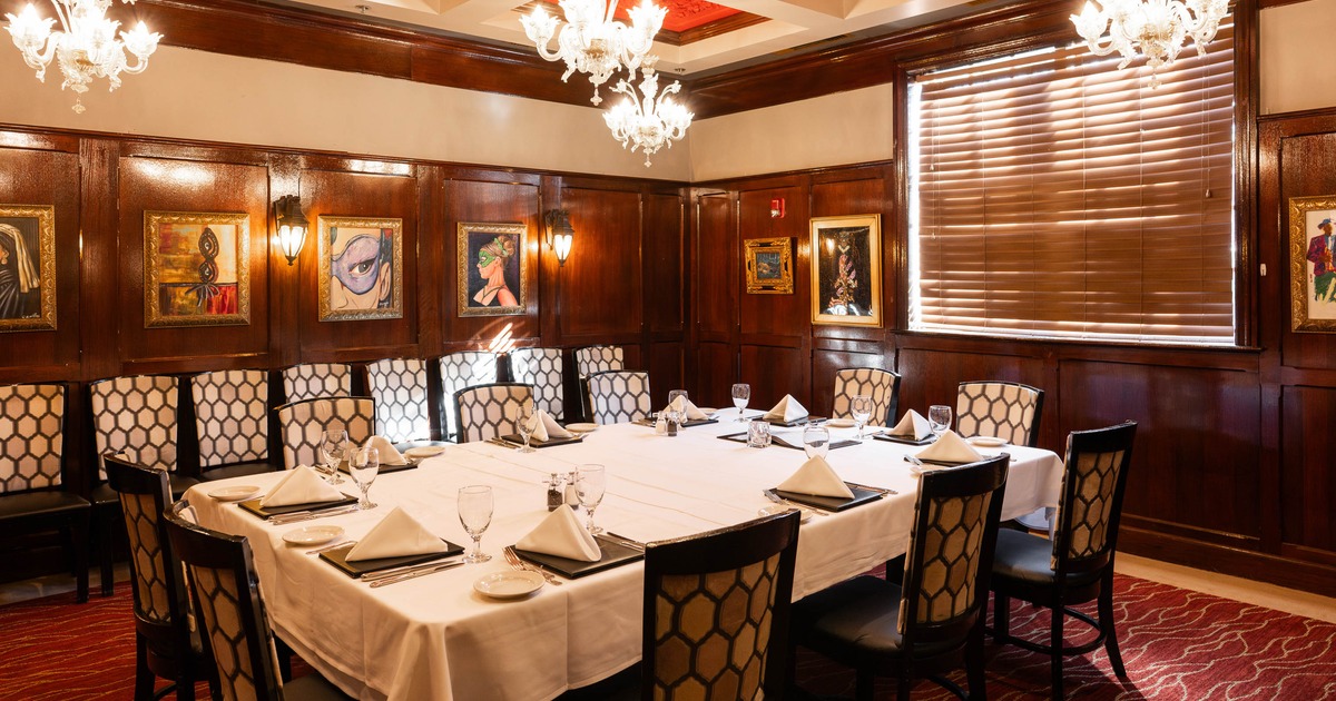 A private dining room with a large table, wooden paneling with framed paintings