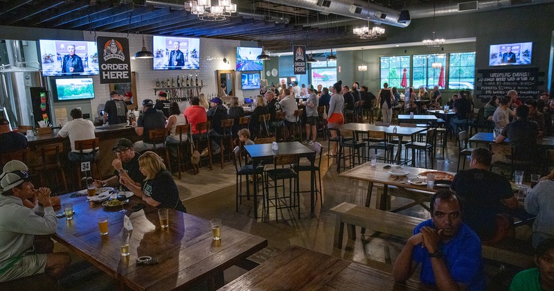 Interior space, bar and seating area full of guests enjoying their food and drinks