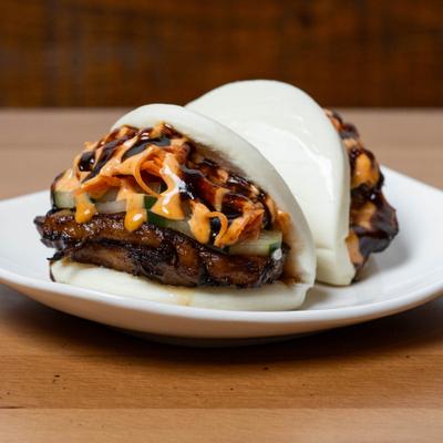 Pork belly buns topped with cucumber and a sauce drizzle.