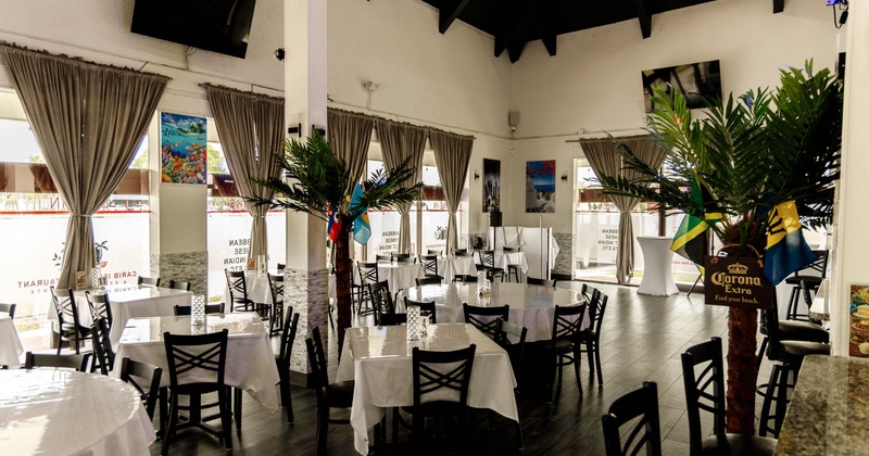 Interior of a restaurant featuring round tables with white tablecloths, black wooden chairs