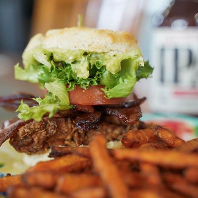 Fried Chicken Skin BLT Biscuit sandwich served with sweet potato fries.