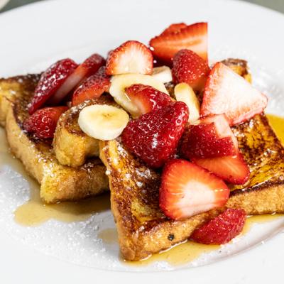 French toast topped with fresh strawberries, banana slices and maple syrup.