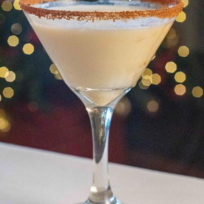 A creamy cocktail in a martini glass with a cinnamon sugar rim.