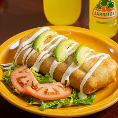 Burrito, topped with avocado, sour cream, lettuce, and tomato.