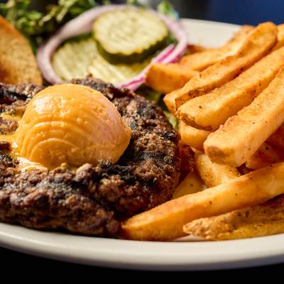 Burger steak served with a scoop of butter on top, fries, salad and bread.