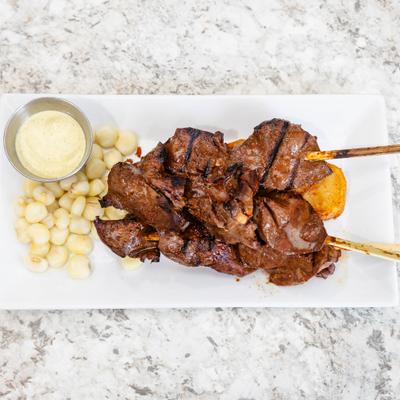 Skewered grilled beef hearts paired with Peruvian corn, potatoes, and dipping sauce.