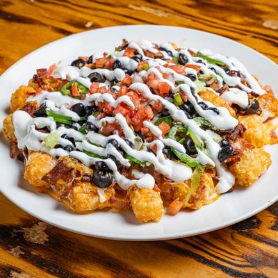 Tater tots topped with melted cheddar, beans, olives, pico de gallo and jalapenos,.