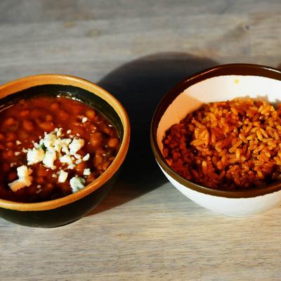 A bowl of Spanish rice and a bowl of pinto beans on a table.