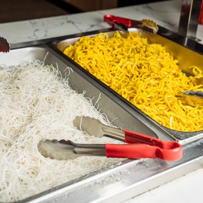 Two large metal buffet trays filled with white and yellow asian noodles.