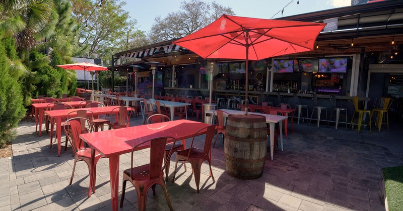 Patio with guest's tables, red sunshade umbrellas, heaters and covered bar