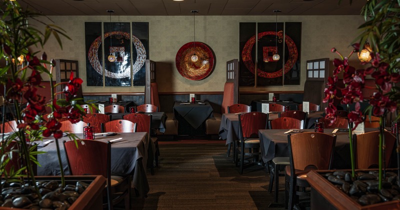 Modern interior with wooden tables, dark tablecloths and abstract wall art.