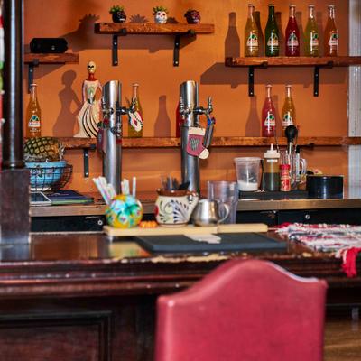 Drink taps and bottled sodas behind the wooden bar counter.