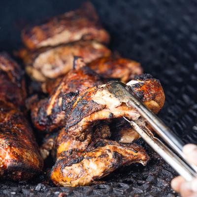 Jerk chicken being cooked on a charcoal grill.