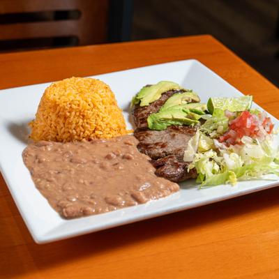 Carne asada plate with rice, beans and a salad.