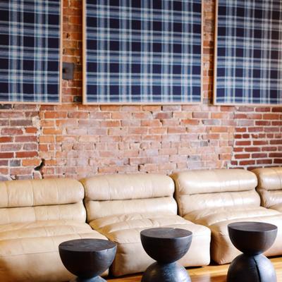 Beige lounge seating with plaid wall art and round black tables.
