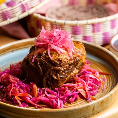Braised pork shank over spicy red slaw topped with pickled onions.