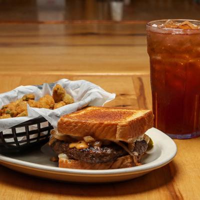 Patty Melt served with a side of fried okra and a iced drink.