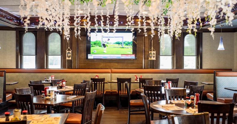 Interior - wooden tables & chairs, decorative hanging foliage, padded booths & a large TV.