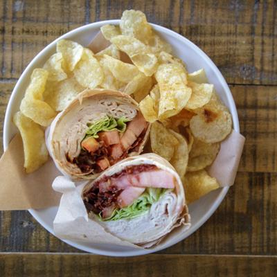 Turkey BLT Wrap with potato chips on the side.