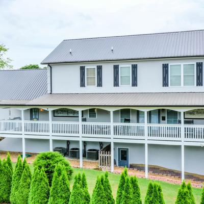 Two-story building with a balcony and evergreen trees surrounding it.