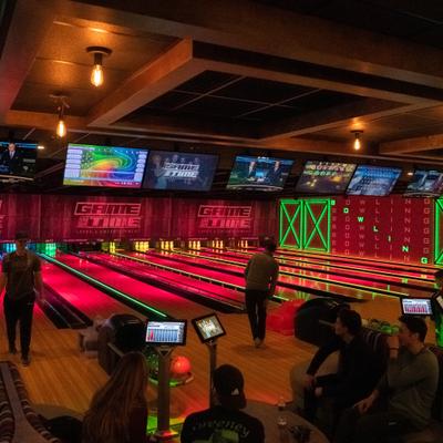 People bowling and sitting at the bowling area.