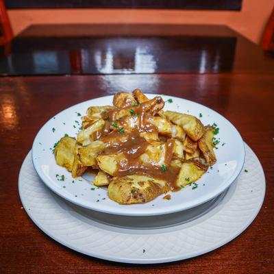 Poutine served with rich gravy on a white plate.