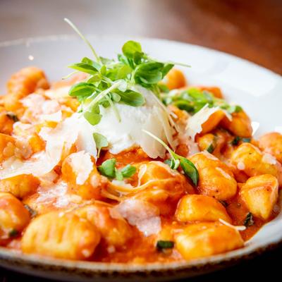 Gnocchi  with tomato sauce, topped with ricotta and micro greens