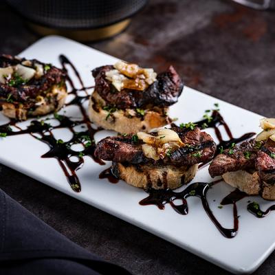 Filet mignon on grilled bread with mustard, topped with balsamic reduction.