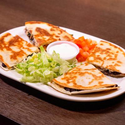 Chicken and black bean quesadilla served with lettuce, diced tomatoes, and sour cream.