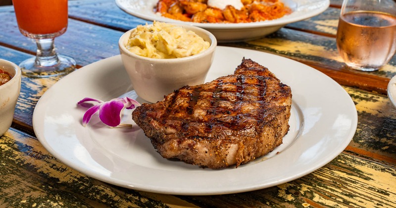 Ribeye served with garlic mashed potatoes on a table with food and drinks