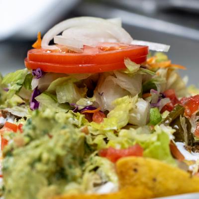 Close-up of guacamole with tortilla chips, tomatoes, and onions.