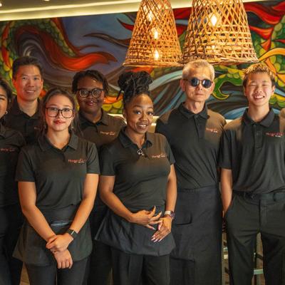 Restaurant staff posing together in dining area.