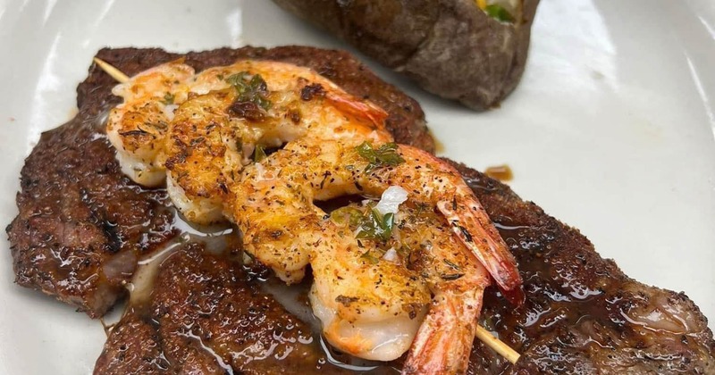 Grilled steak topped with shrimp and served with loaded baked potato
