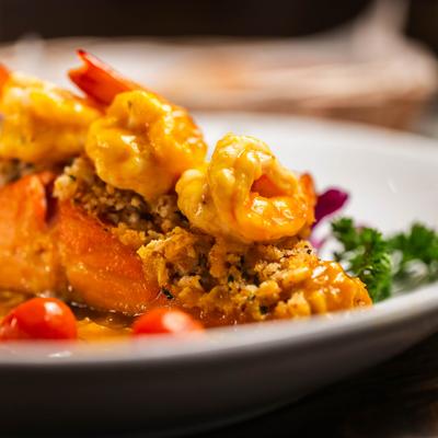 A close-up view of a salmon with a crab crust and shrimp.