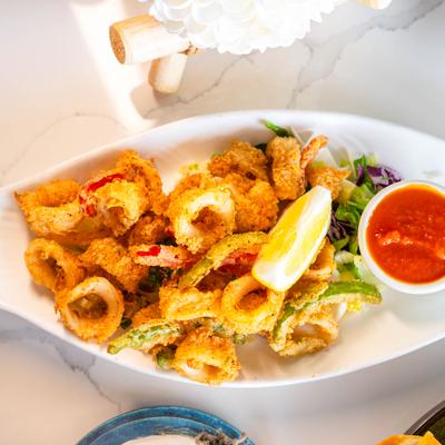 Fried calamari with marinara sauce and a lemon wedge.