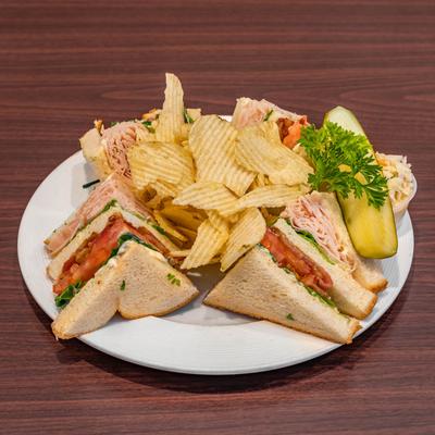 Club sandwiches, with a side of potato chips.